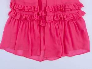 Détail de volants superposés sur une robe longue en mousseline magenta de vacances
