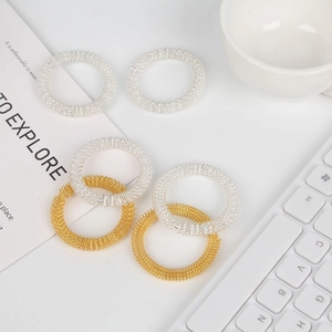 Assorted gold and silver acupressure massage rings on a bright desk background