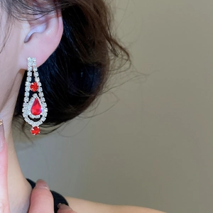 Detail of luxury drop-shaped red gemstone earrings with silver fringes on a female model