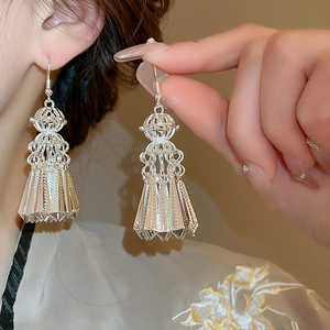 Macro detail of silver tassel earrings with lantern design and intricate metal fringe