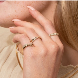 Macro shot of three irregular gold titanium rings with zircon stones on model's hand