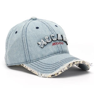 Detail of light blue denim baseball cap showing 3D MGCANN embroidery and leopard print brim