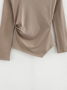 Detail of knit fabric texture with side ruching and asymmetrical hemline on brown top