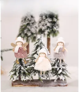 Detailed view of plush Christmas angel dolls with glitter wings on a rustic wooden base
