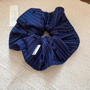 Détail du chouchou rayé bleu marine avec étiquette Happiness sur fond textile beige