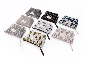 Detail view of eight printed canvas pouches with diverse patterns and leather zipper pulls