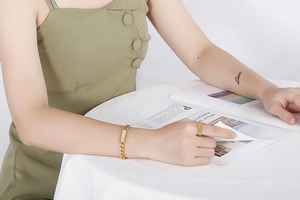 Detailed view of a gold-plated Cuban chain bracelet and matching ring on a model's wrist