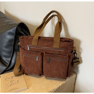 Close-up of brown corduroy tote bag with multiple zipper pockets and adjustable strap