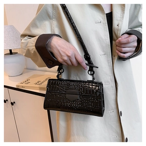 Chic lifestyle view of black crocodile pattern handbag paired with a beige trench coat