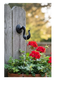 Detail showing a vintage black cast iron S-shaped hook mounted on a wooden fence