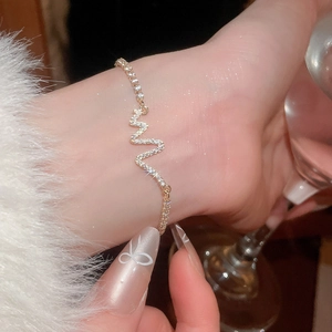 Detail of elegant gold bracelet featuring a shimmering zircon heartbeat line design