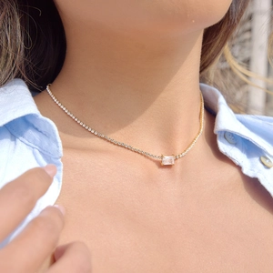 Elegante goldfarbene Tennis-Halskette mit rechteckigem Zirkonia-Anhänger an einer Frau