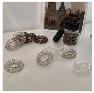 Close-up of spiral hair ties in black, grey, and coffee colors on a white surface