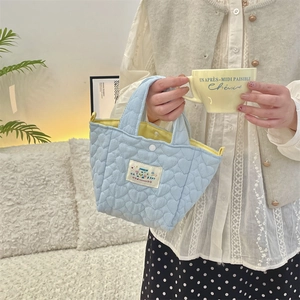 Detail of light blue quilted heart tote with bright yellow lining and snap closure