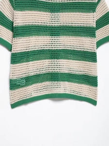 Detailansicht des grün-weiß gestreiften Strickgewebes mit Lochmuster auf dem Polo-Top
