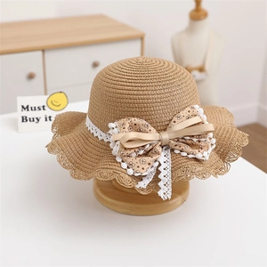 Close-up of straw sun hat featuring beige lace trim and a large floral bow detail