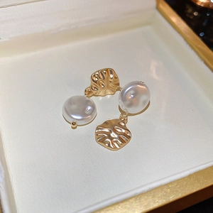 Detail of irregular gold hammered metal earrings with elegant white faux pearl drop