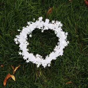 Top view of white five-pointed star tinsel garland for Christmas decoration on green grass