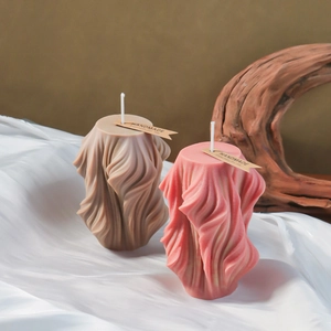 Detail of spiral wave textured candle with handmade tag on white fabric backdrop