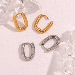 Close-up of gold and silver textured earrings with water droplets and ice blocks