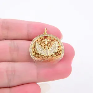 Macro view of gold-plated hollow disc pendant with micro-paved crystals and dove icon