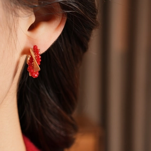 Close-up of elegant gold hoop earring with red glass bead on ear for a retro style