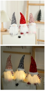 Close-up of three glowing faceless Christmas gnomes with sequins in day and night lighting