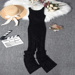 Detailed view of black lace jumpsuit with hollow patterns on white fur and grey carpet