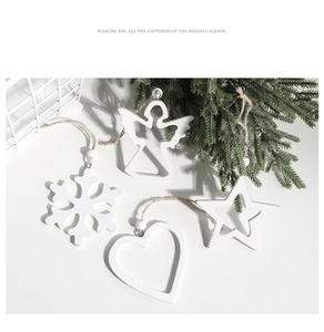 Detailed view of white wooden Christmas ornaments with snowflake and angel shapes on pine branch