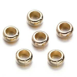 Macro detail of six polished gold-tone round spacer beads for DIY jewelry making