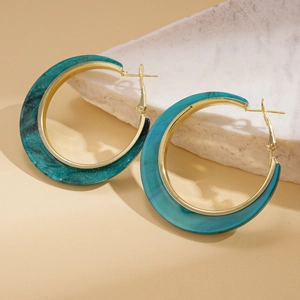 Detailed close-up of blue marble acrylic hoop earrings with golden metal inner band