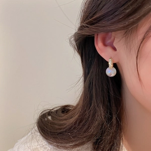 Détail de boucles d'oreilles pendantes en perles nacrées et plaqué or élégant