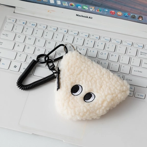 Detail of plush rice ball coin purse with big eyes and coil strap on laptop