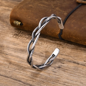 Detail of silver twisted metal cuff bracelet on rustic wood background with leather pouch