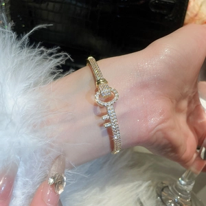 Close-up of 18k gold plated key-shaped bangle with pavé zircons on woman's wrist
