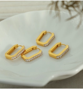 Macro view of gold rectangular hoop earrings with pavé cubic zirconia on a ceramic dish