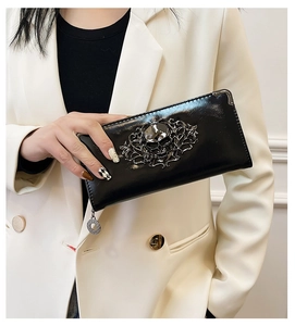 Detail of a black skull long wallet held by a model in a blazer for a chic look