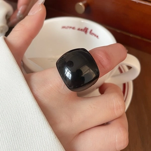 Close-up of a large black resin geometric ring worn while holding a coffee cup