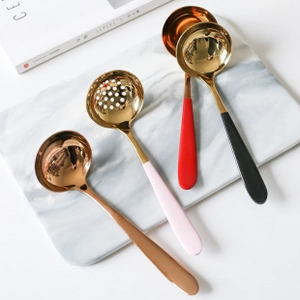 Detail of colorful stainless steel soup spoons and colander on white marble
