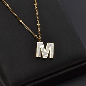 Minimalist gold titanium necklace with M letter mother of pearl pendant on jewelry box