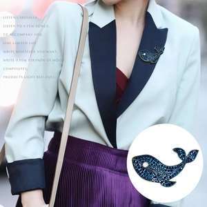 Détail de la broche baleine en strass bleus avec perle sur un tailleur vert clair