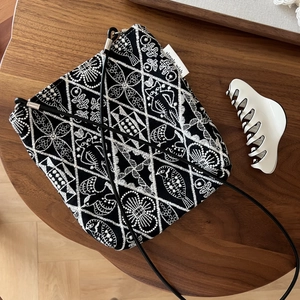 Close-up of bird and floral embroidery on a black canvas crossbody bag with rope strap