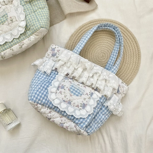 Detail of checkered quilted tote bag with white lace ruffle and cute bear patch