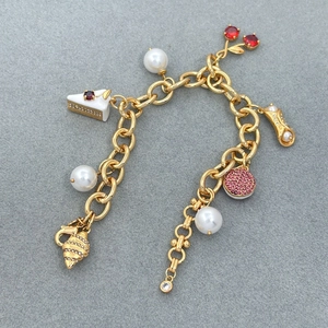 Golden charm bracelet with cherry, pearl, and zircon pendants on grey texture background