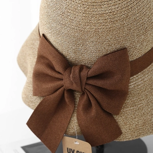 Detail of summer straw hat texture with brown ribbon bow and UV protection tag