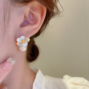 Elegant gold flower earrings with white petals and pearls on a female model