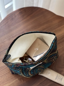 Detailed macro shot of vintage jacquard fabric and golden paisley embroidery on makeup bag