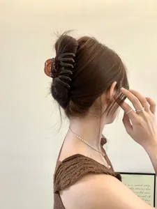 Detail of amber large shark hair claw clip securing a high bun on female hair