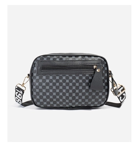 Close-up of black crossbody bag with quilted dots and stylish wide graphic strap