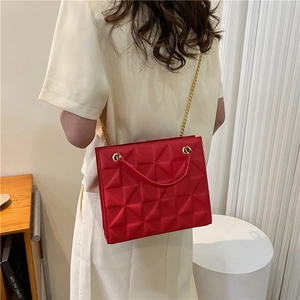 Detail of red geometric textured shoulder bag with golden chain strap on model back